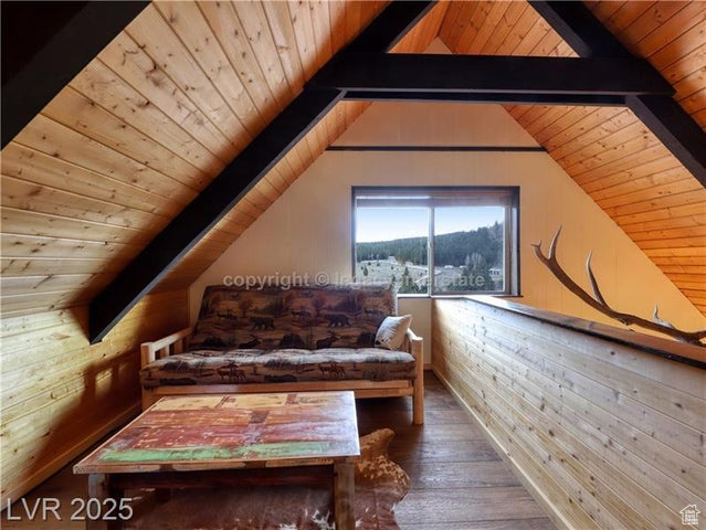 Sitting room featuring vaulted ceiling with beams, wood walls, wooden ceiling, and hardwood / wood-style flooring