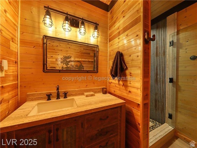 Bathroom featuring wooden walls, vanity, and a shower stall