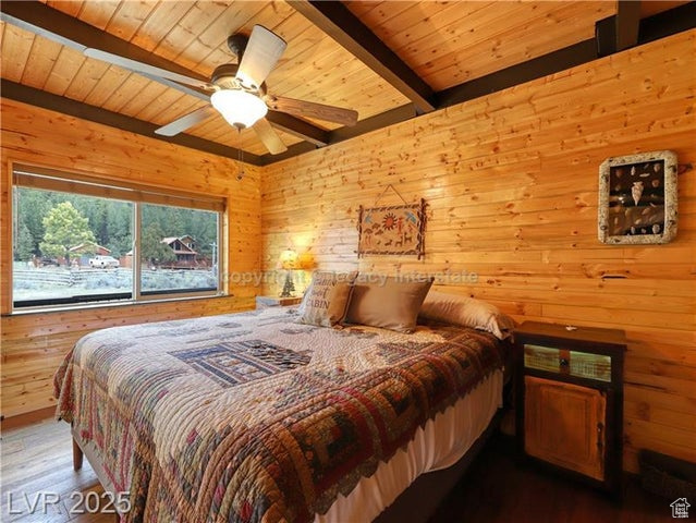 Bedroom featuring wood walls, wood finished floors, wooden ceiling, and beamed ceiling