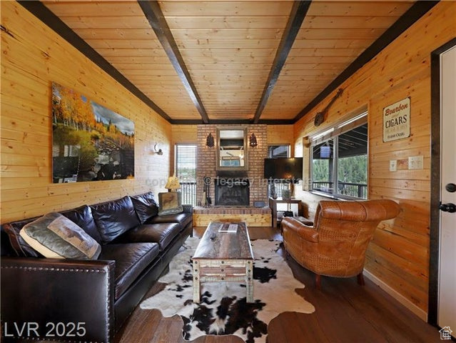 Living area featuring wood walls, a brick fireplace, wood finished floors, beamed ceiling, and wood ceiling