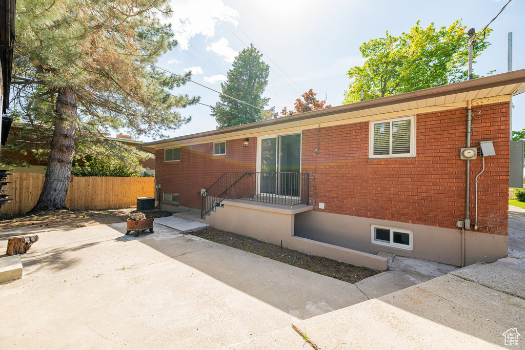 Back of house with fence, a patio area, and brick siding