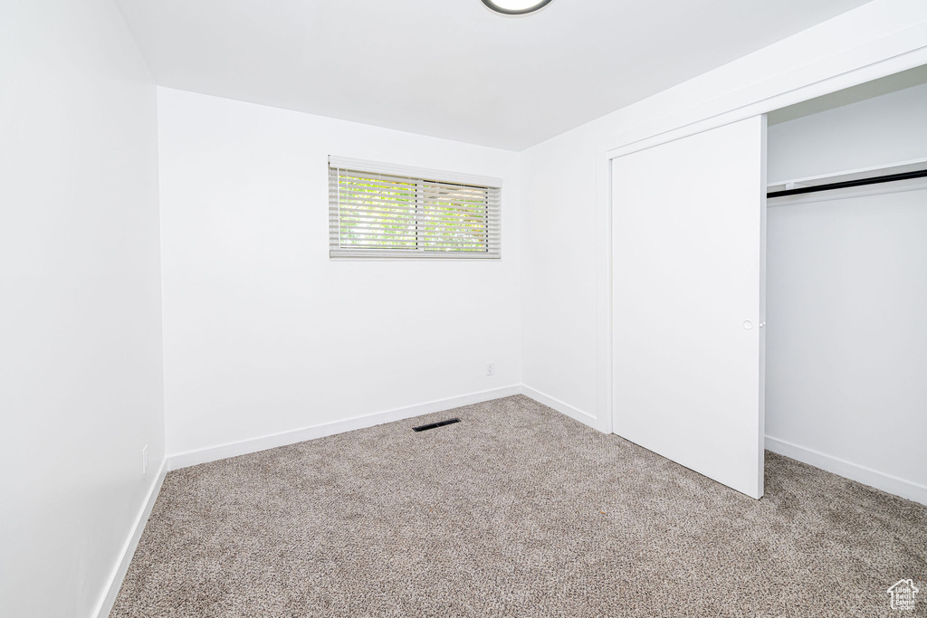 Unfurnished bedroom featuring a closet, carpet, and baseboards