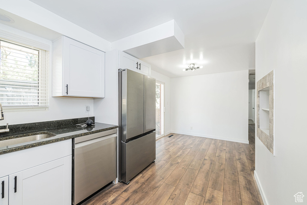 Kitchen with a sink, wood finished floors, white cabinets, and stainless steel appliances