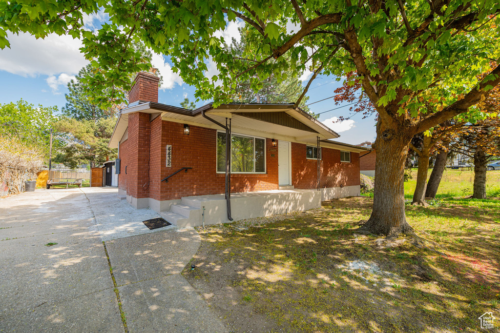 View of home\'s exterior with concrete driveway, brick siding, and a chimney