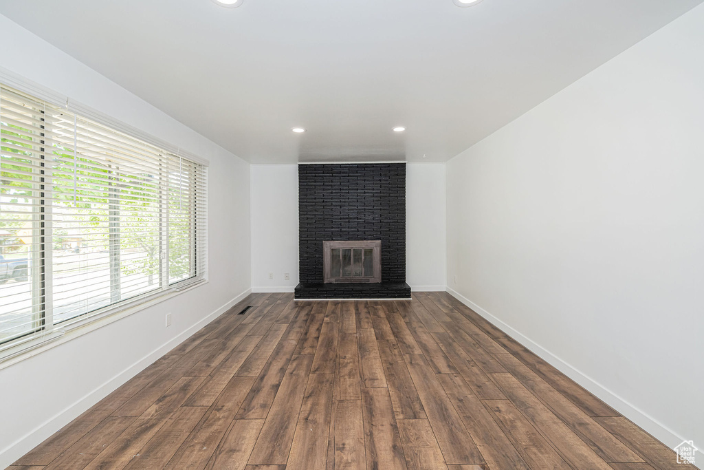 Unfurnished living room with recessed lighting, baseboards, a fireplace, and dark wood-style flooring