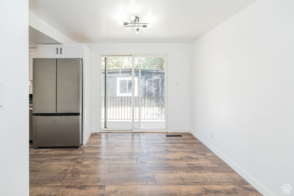 Unfurnished dining area featuring visible vents, dark wood-style flooring, and baseboards