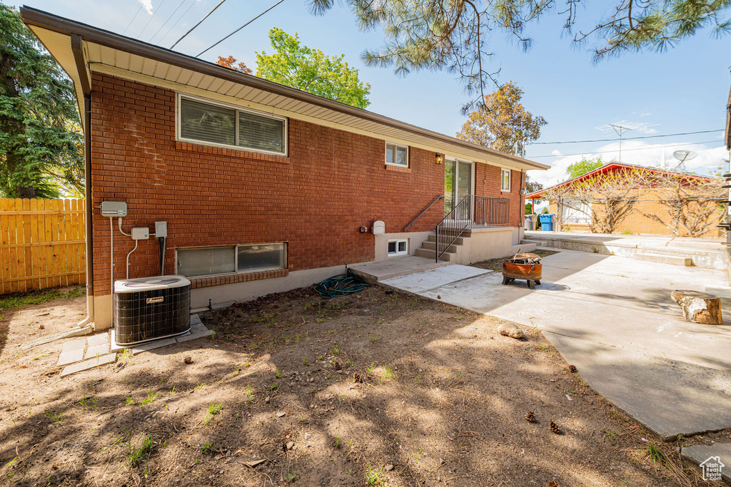 Back of house featuring brick siding, central AC, fence, and a patio area