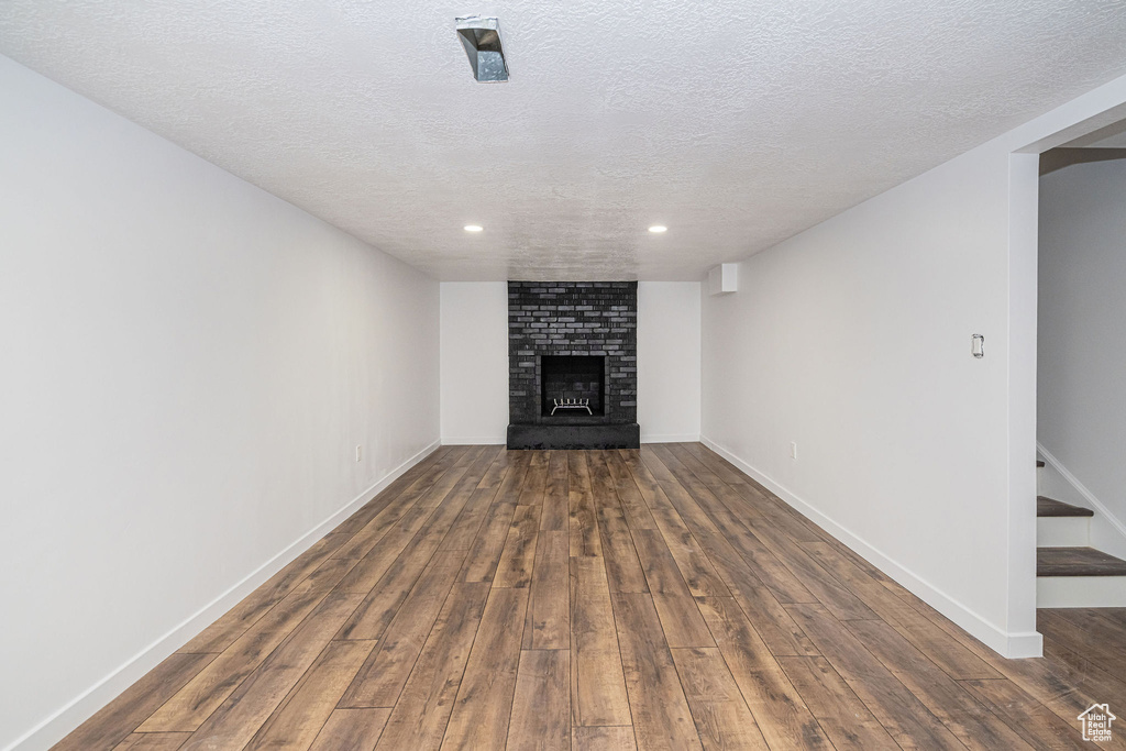 Unfurnished living room with baseboards, a brick fireplace, recessed lighting, and wood finished floors