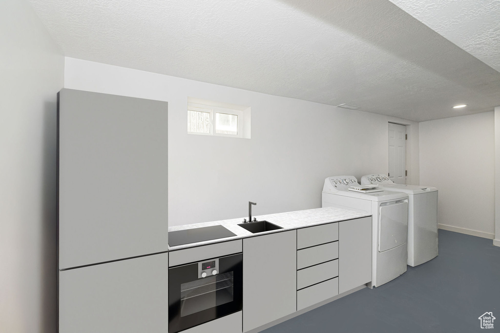 Laundry room featuring cabinet space, a sink, a textured ceiling, recessed lighting, and washer and clothes dryer