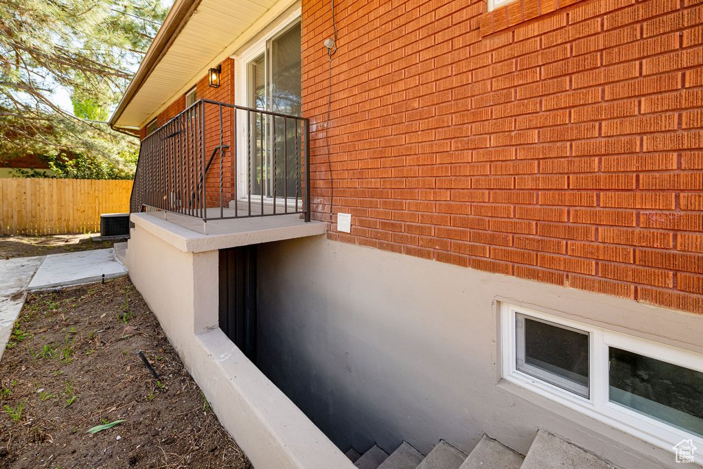 View of side of property featuring brick siding, fence, and cooling unit