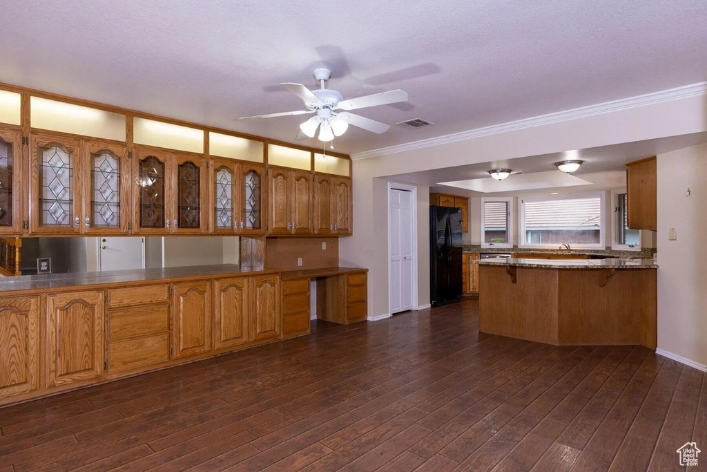 Kitchen featuring freestanding refrigerator, a peninsula, a kitchen breakfast bar, ceiling fan, and brown cabinets