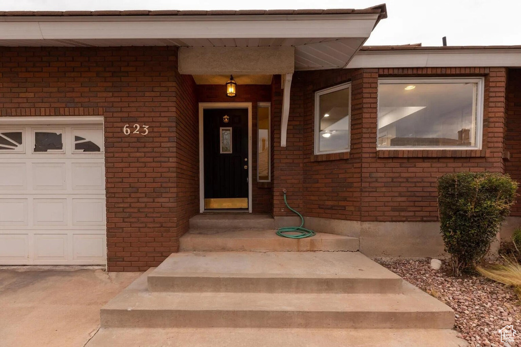 View of exterior entry with brick siding and a garage