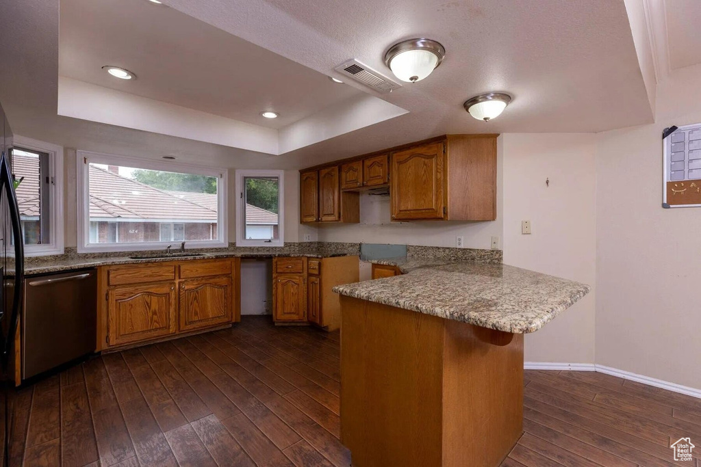 Kitchen with stainless steel dishwasher, visible vents, a raised ceiling, a sink, and dark wood finished floors