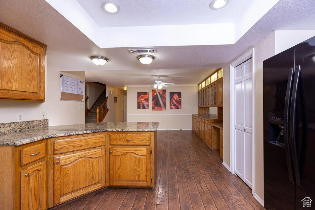 Kitchen with visible vents, brown cabinetry, a peninsula, black refrigerator with ice dispenser, and dark wood-type flooring