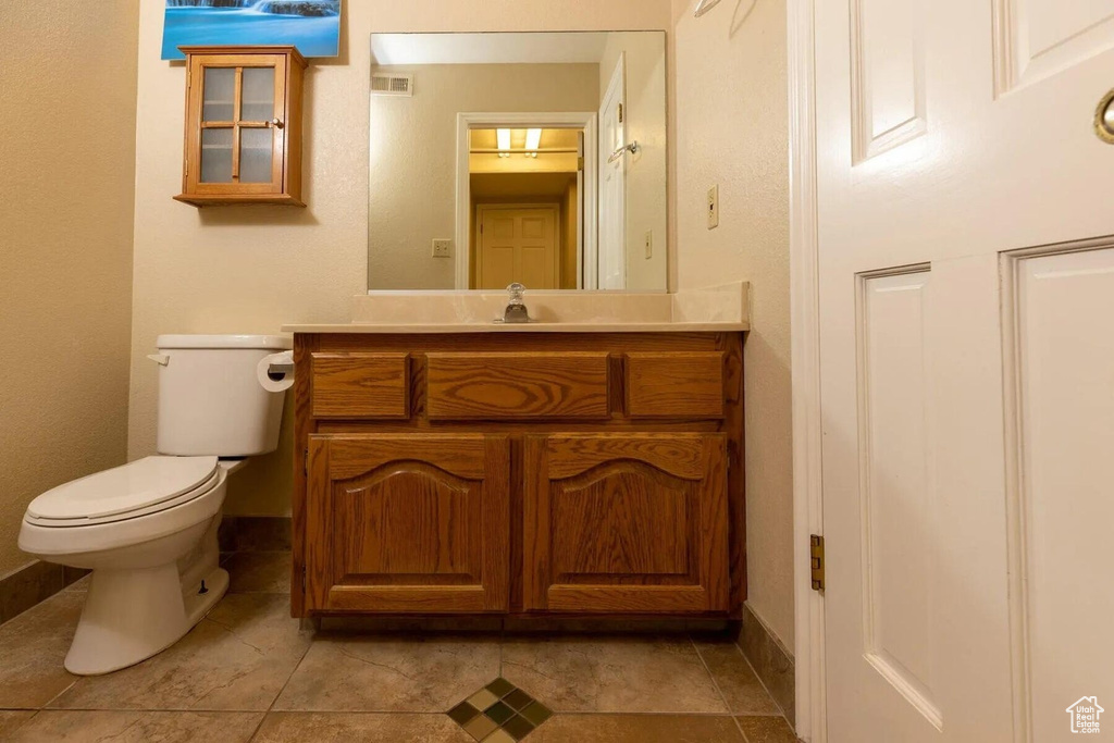 Half bathroom featuring baseboards, vanity, toilet, and visible vents