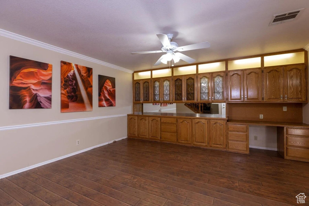 Kitchen with visible vents, ornamental molding, glass insert cabinets, ceiling fan, and built in desk