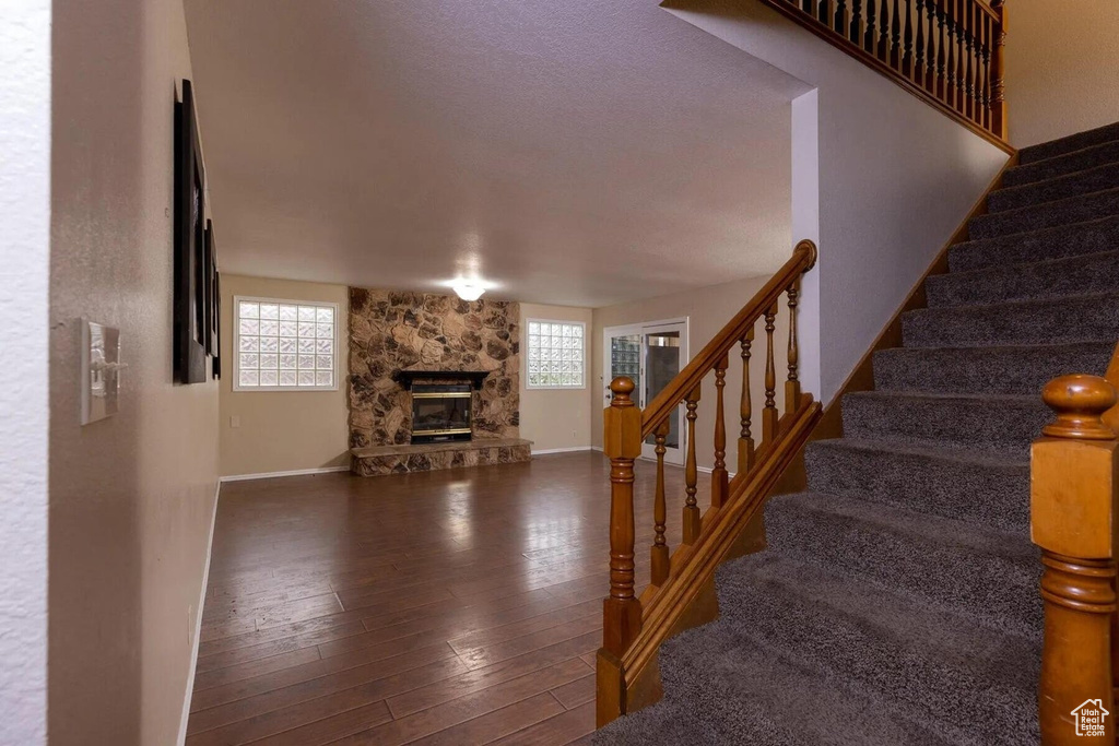 Stairs with baseboards, hardwood / wood-style flooring, a stone fireplace, and a wealth of natural light