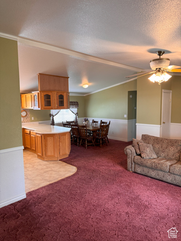 Carpeted living room featuring ceiling fan, ornamental molding, a textured ceiling, and lofted ceiling