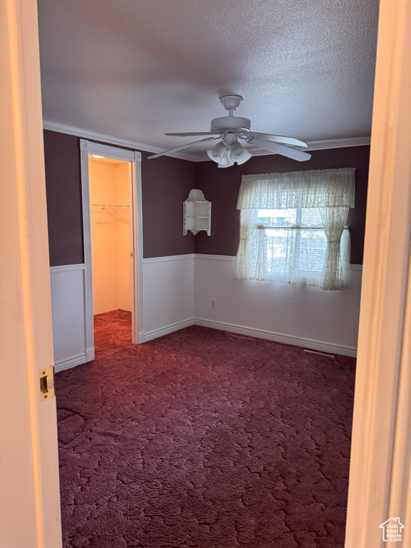 Carpeted empty room with ceiling fan and a textured ceiling