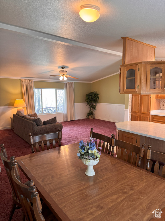 Carpeted dining room featuring wainscoting, ceiling fan, vaulted ceiling, and a textured ceiling