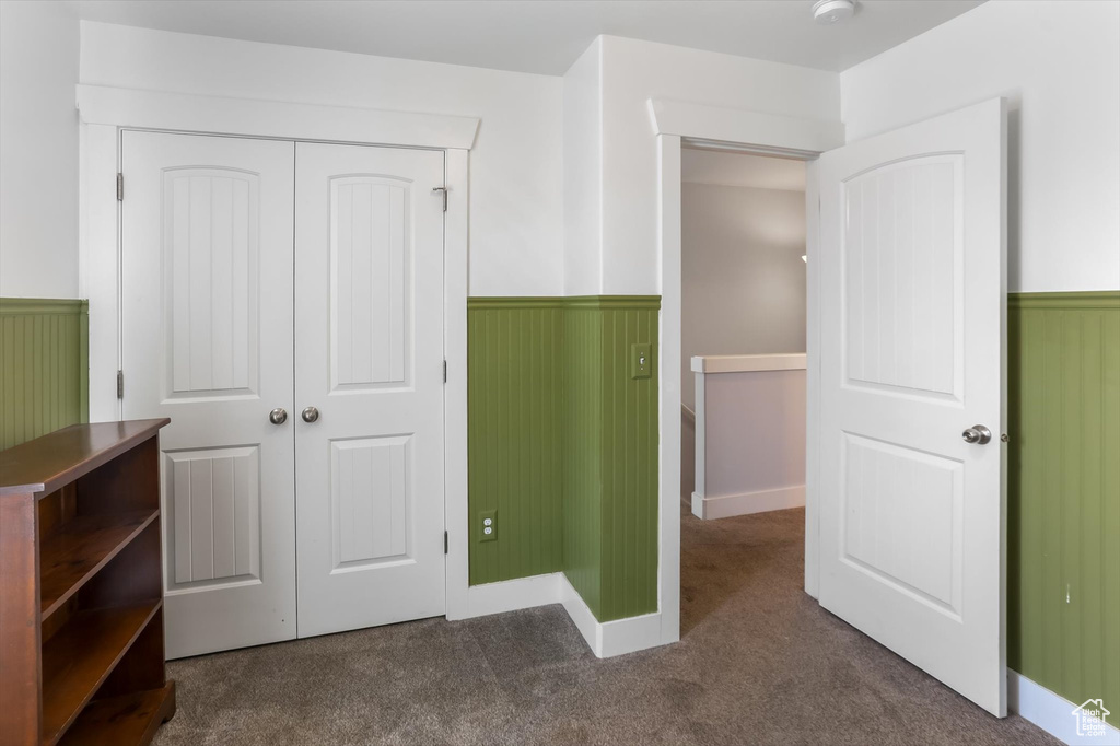 Unfurnished bedroom featuring carpet flooring, a closet, and a wainscoted wall
