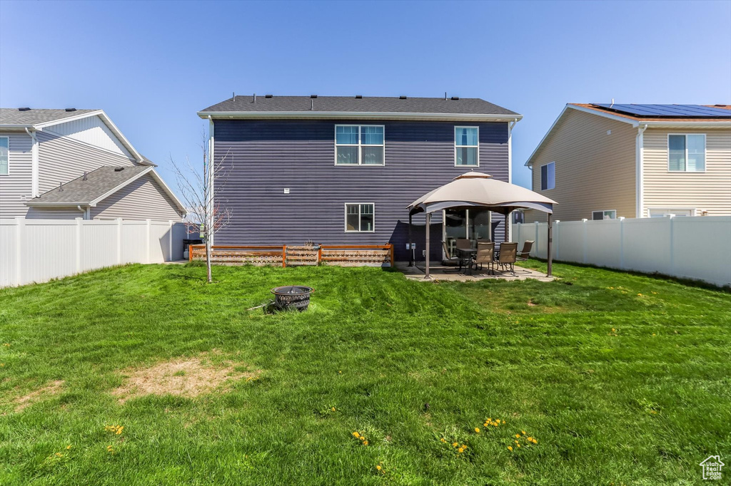 Rear view of property featuring a patio, an outdoor fire pit, a yard, and a gazebo