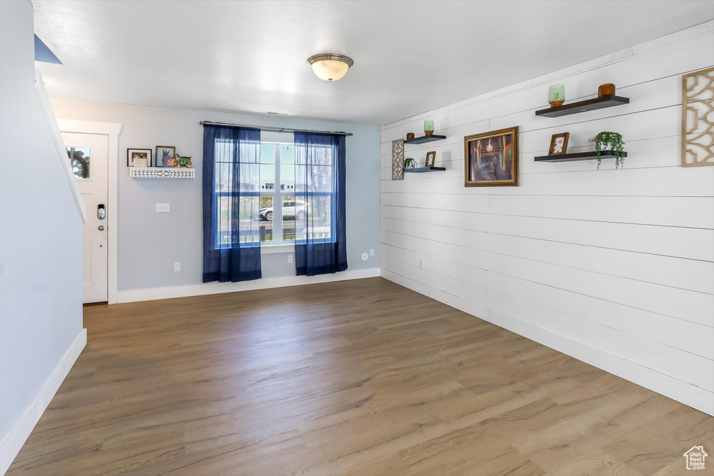 Unfurnished dining area featuring baseboards, wood walls, and wood finished floors