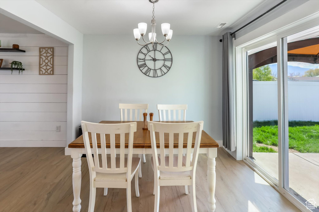 Dining space with plenty of natural light, light wood-style floors, and a chandelier