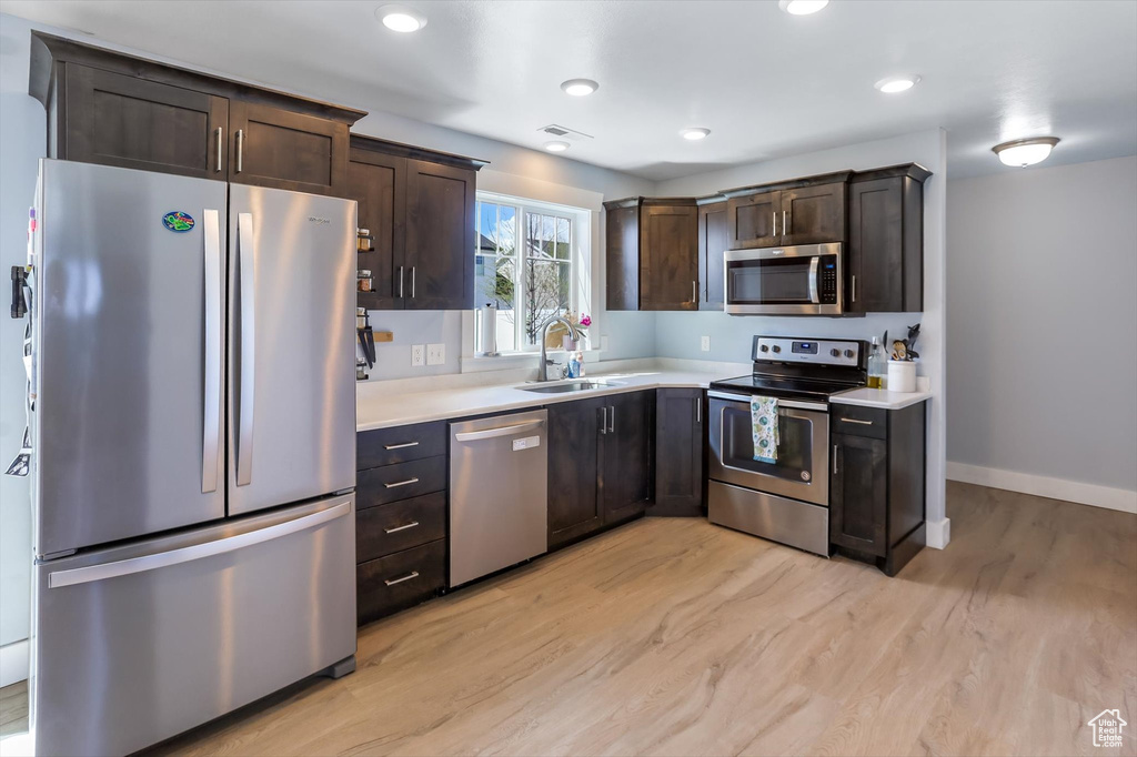 Kitchen featuring light countertops, dark brown cabinetry, appliances with stainless steel finishes, and a sink