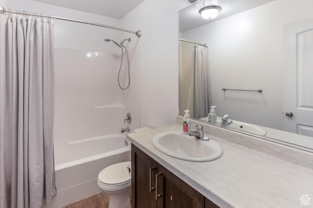 Bathroom with vanity, toilet, wood finished floors, and shower / tub combo with curtain