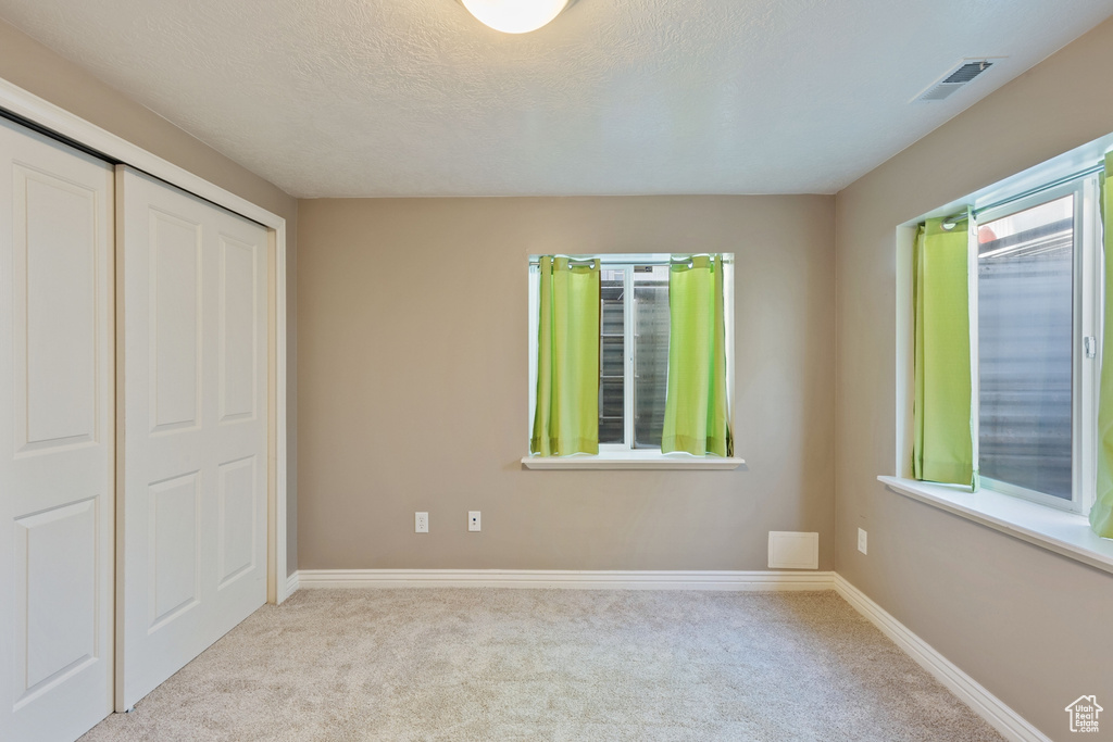 Unfurnished bedroom featuring baseboards, carpet, a closet, and visible vents