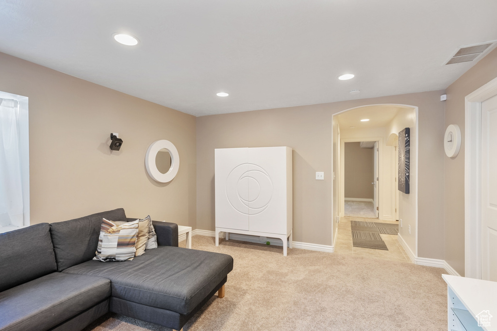 Living room featuring light carpet, arched walkways, recessed lighting, baseboards, and visible vents