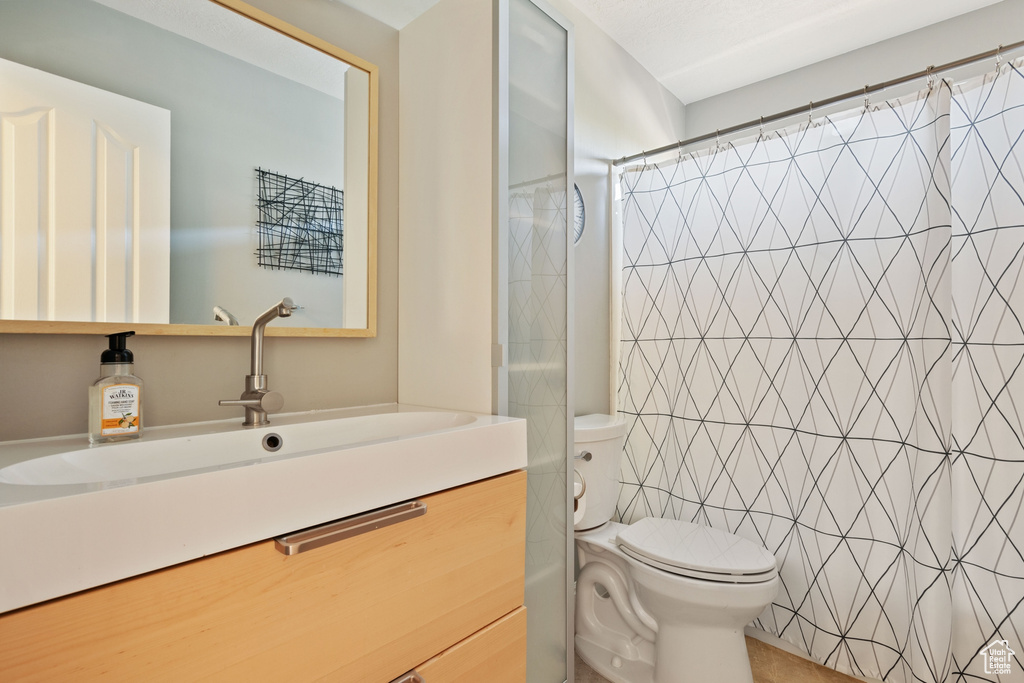 Bathroom with toilet, curtained shower, and vanity