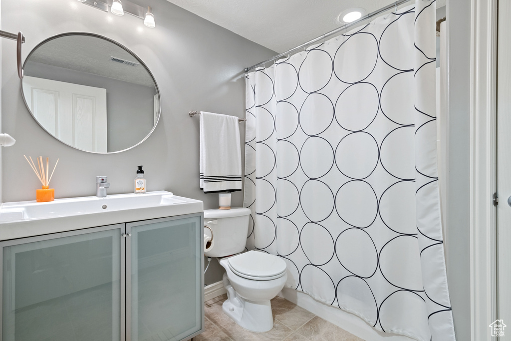 Full bathroom featuring tile patterned flooring, vanity, toilet, curtained shower, and visible vents
