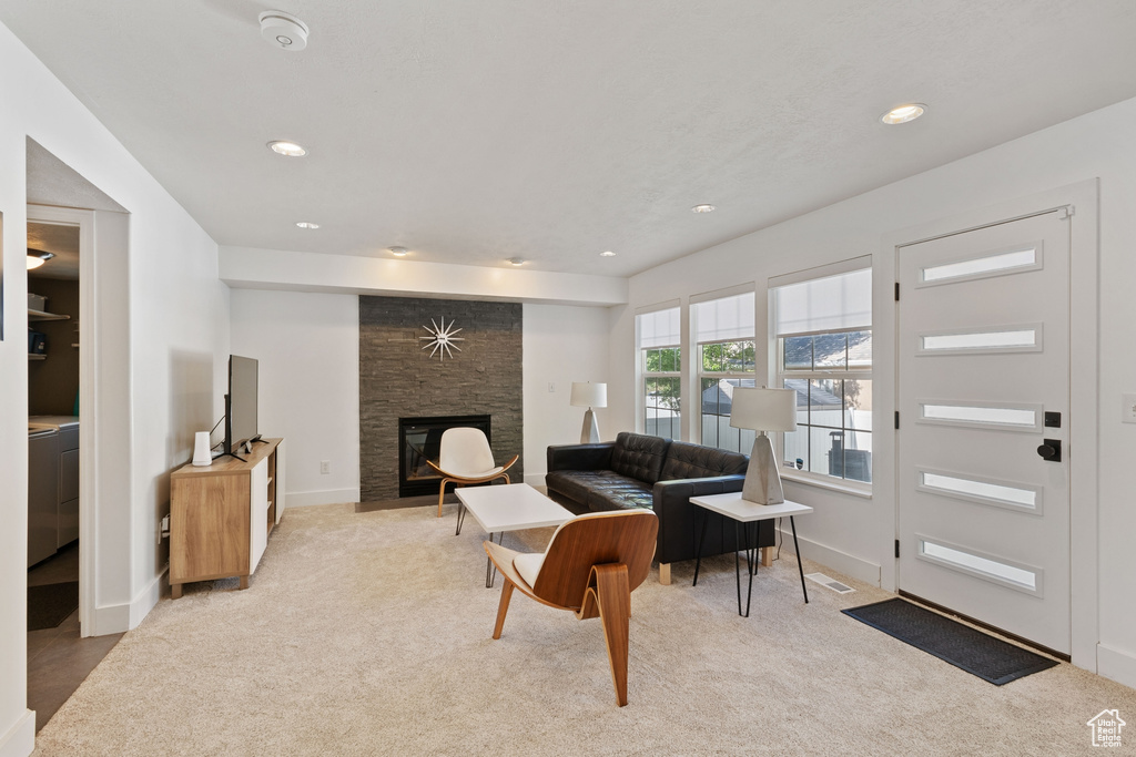 Living room featuring light colored carpet, visible vents, a stone fireplace, and recessed lighting