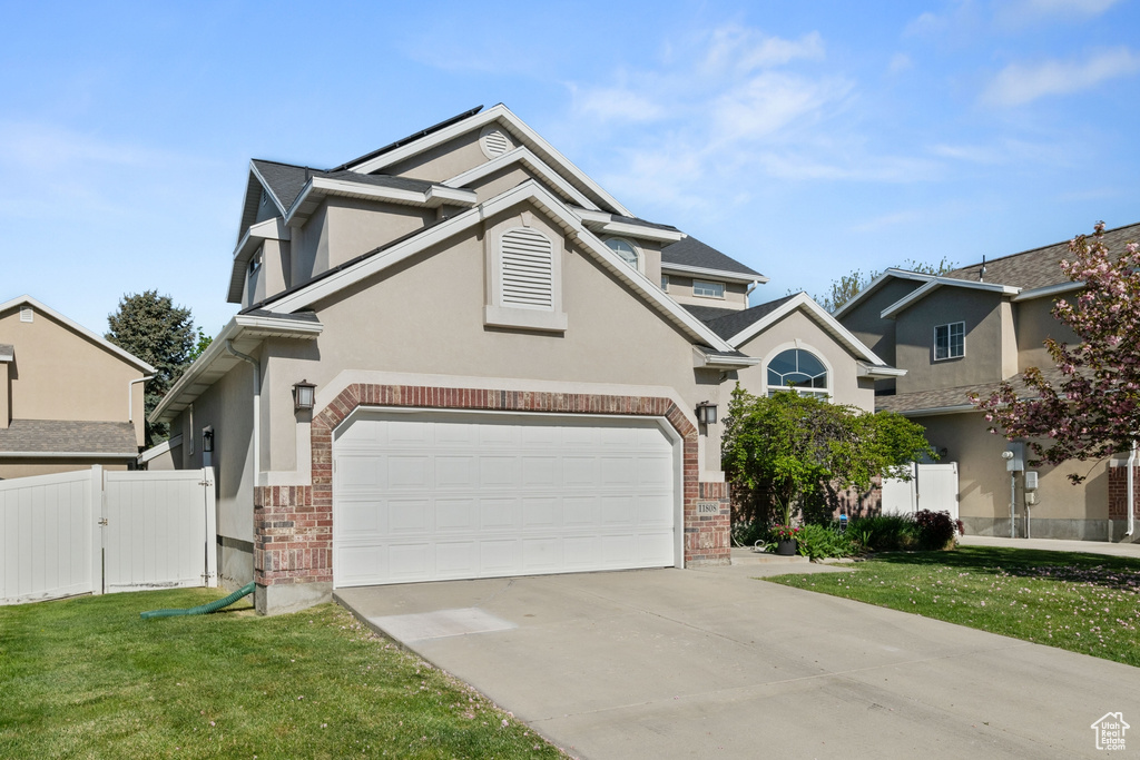 Traditional-style house with driveway, a front yard, a garage, fence, and stucco siding