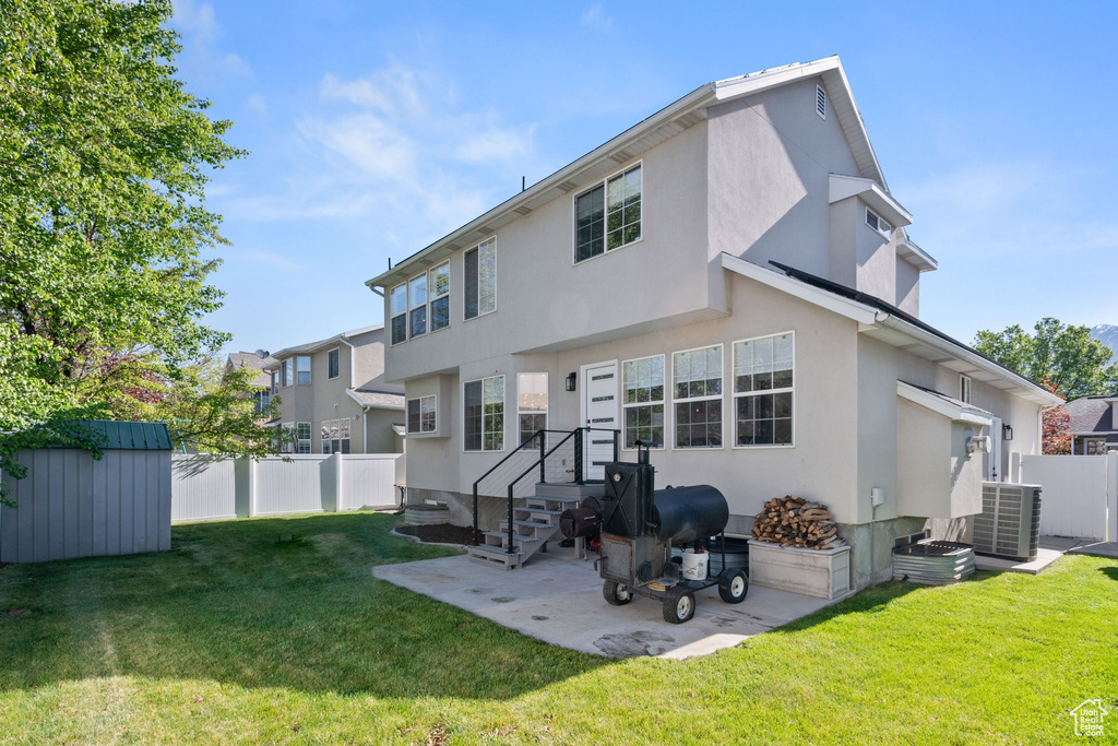 Back of property featuring fence, stucco siding, a shed, an outbuilding, and a lawn