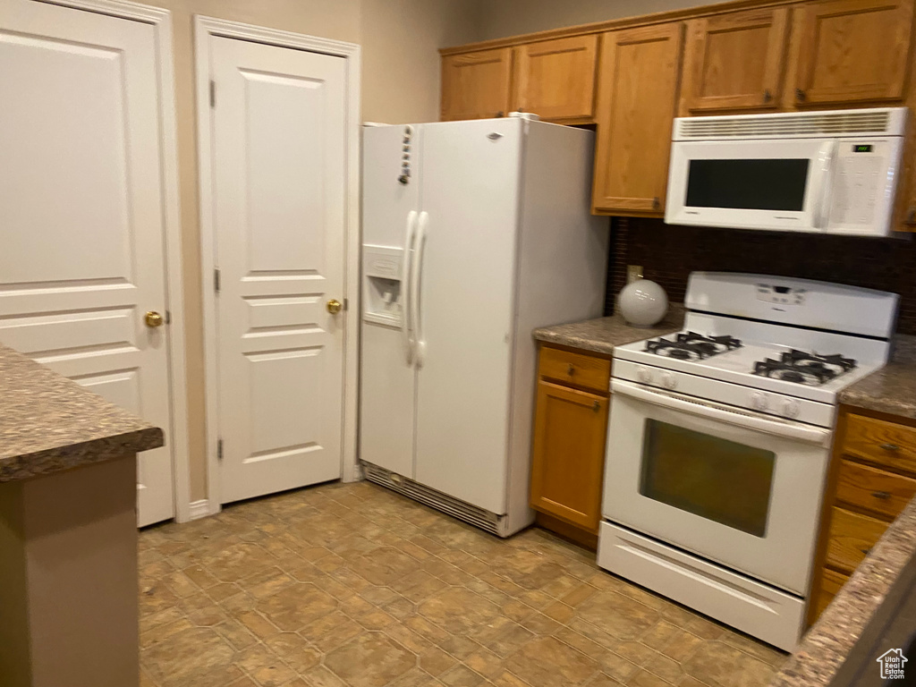 Kitchen with brown cabinetry and white appliances