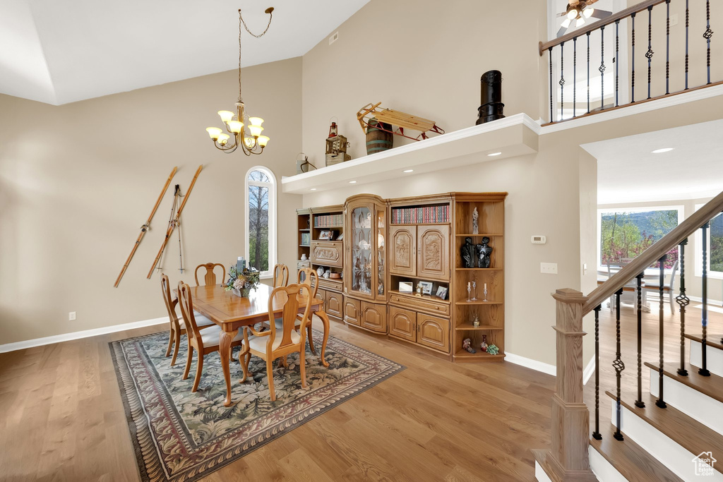 Dining space with high vaulted ceiling, baseboards, stairway, and light wood-type flooring
