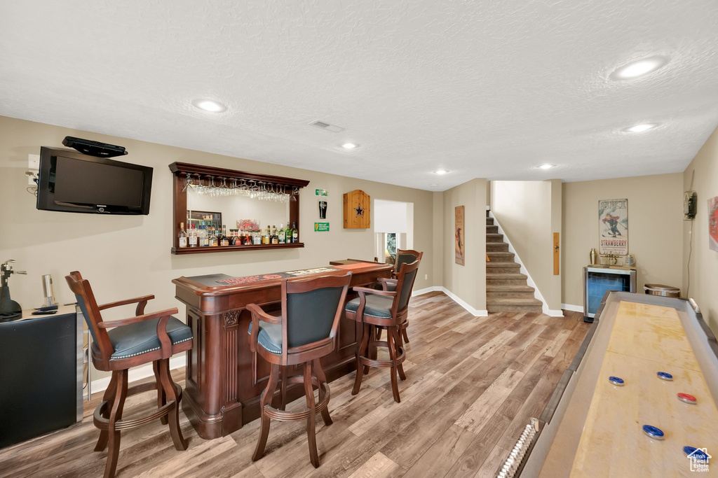 Bar featuring recessed lighting, a textured ceiling, a dry bar, and wood finished floors