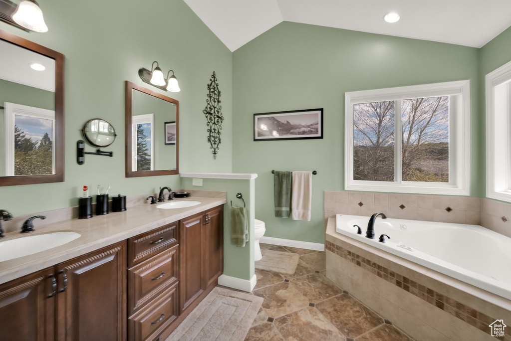Full bath with vaulted ceiling, a wealth of natural light, a sink, and a garden tub