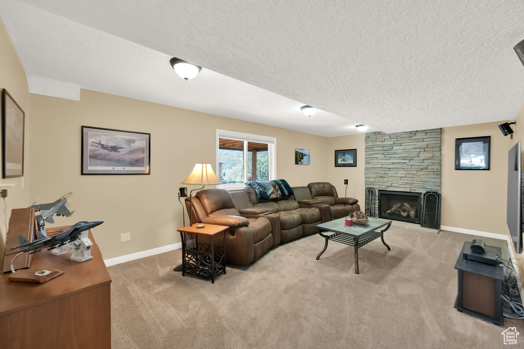 Living room featuring a fireplace, baseboards, light carpet, and a textured ceiling