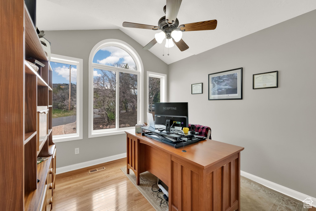 Office space with visible vents, lofted ceiling, baseboards, ceiling fan, and light wood finished floors