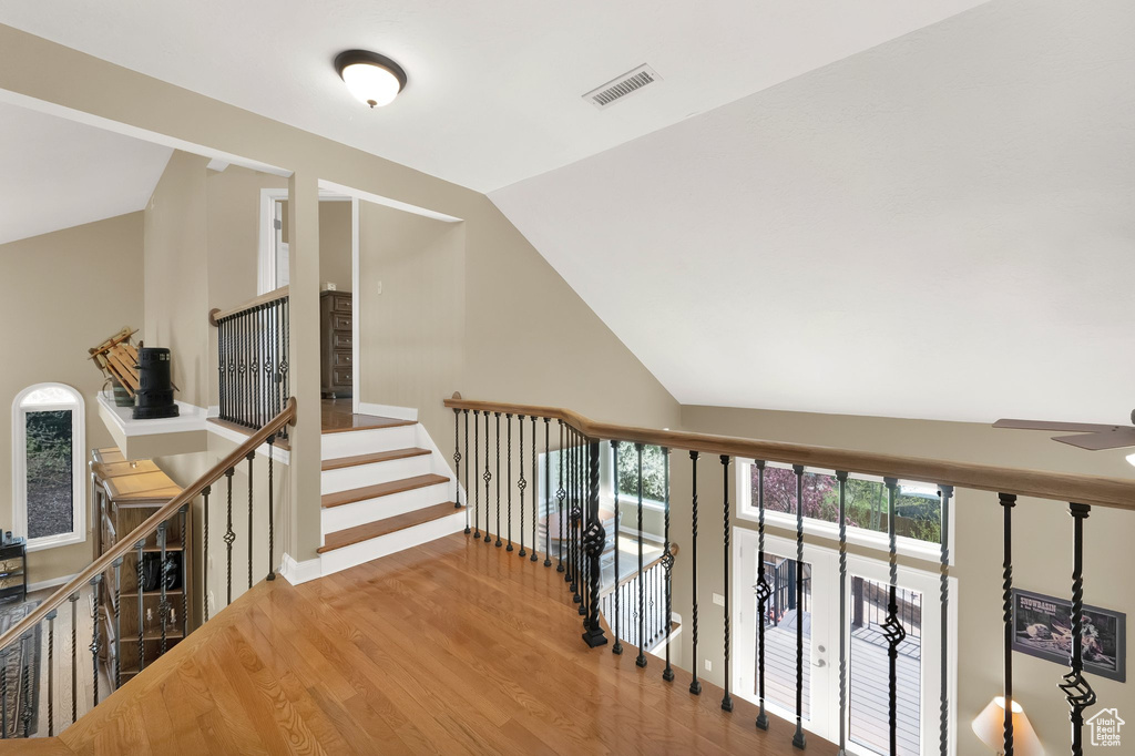 Hall with baseboards, visible vents, wood finished floors, and lofted ceiling