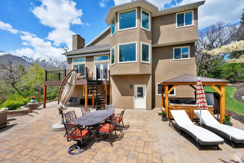 Rear view of property with outdoor dining space, stairs, stucco siding, a chimney, and a patio