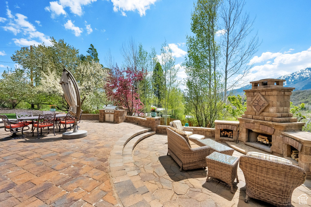 View of patio / terrace with an outdoor living space with a fireplace, outdoor dining area, and exterior kitchen