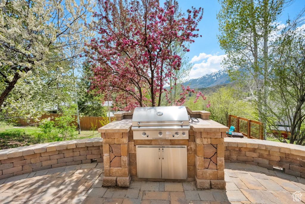 View of patio featuring a mountain view, fence, grilling area, and an outdoor kitchen