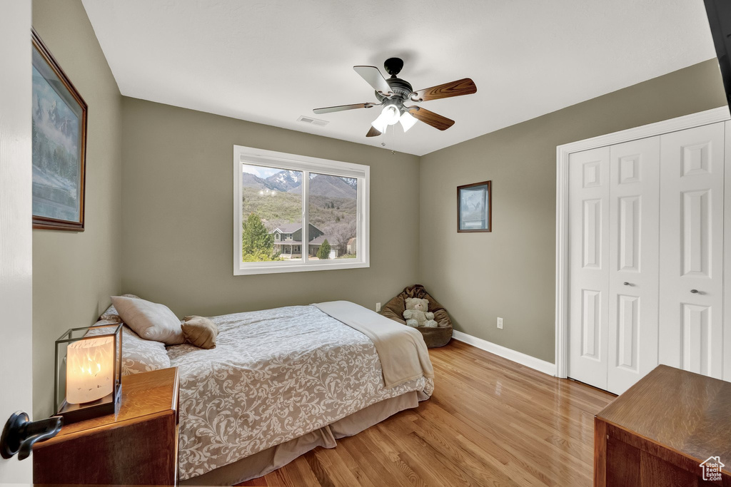 Bedroom featuring visible vents, a closet, baseboards, a ceiling fan, and light wood finished floors
