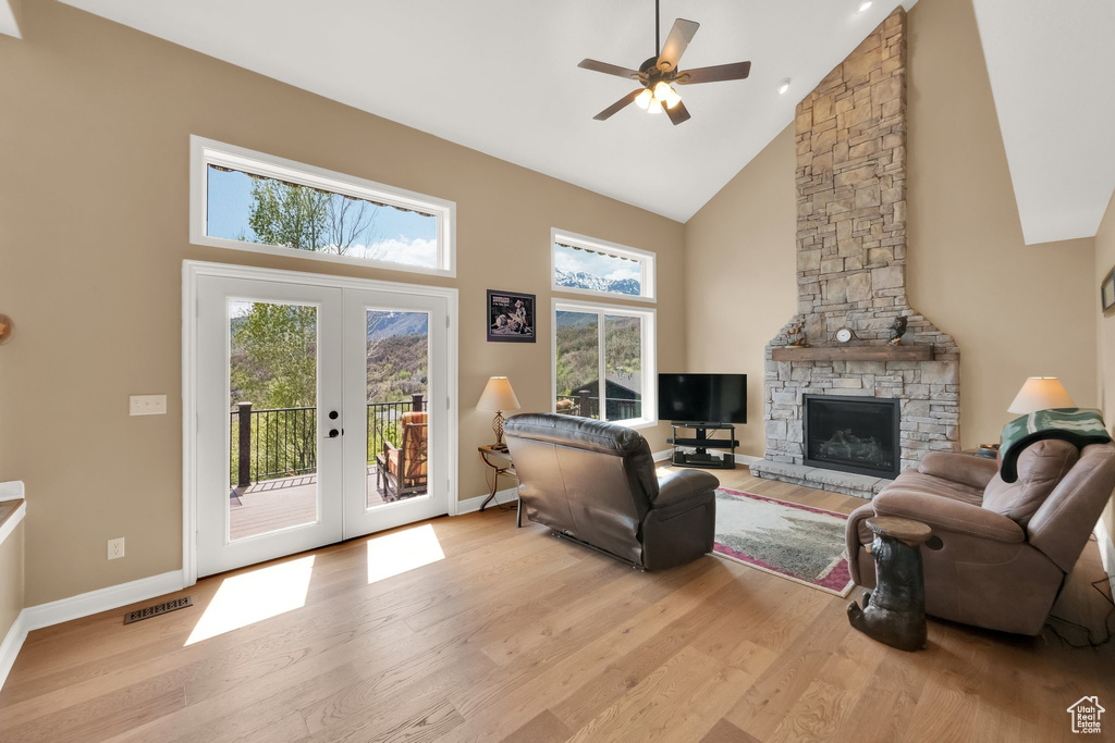 Living area featuring french doors, a ceiling fan, high vaulted ceiling, baseboards, and light wood-style flooring