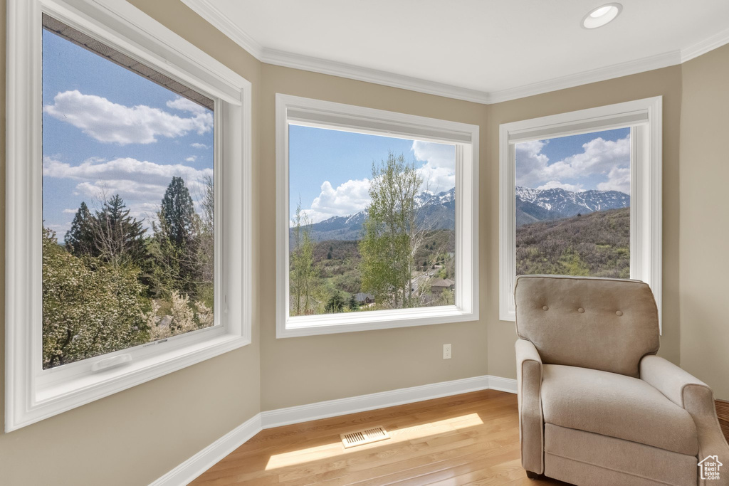 Living area featuring baseboards, a mountain view, crown molding, and wood finished floors